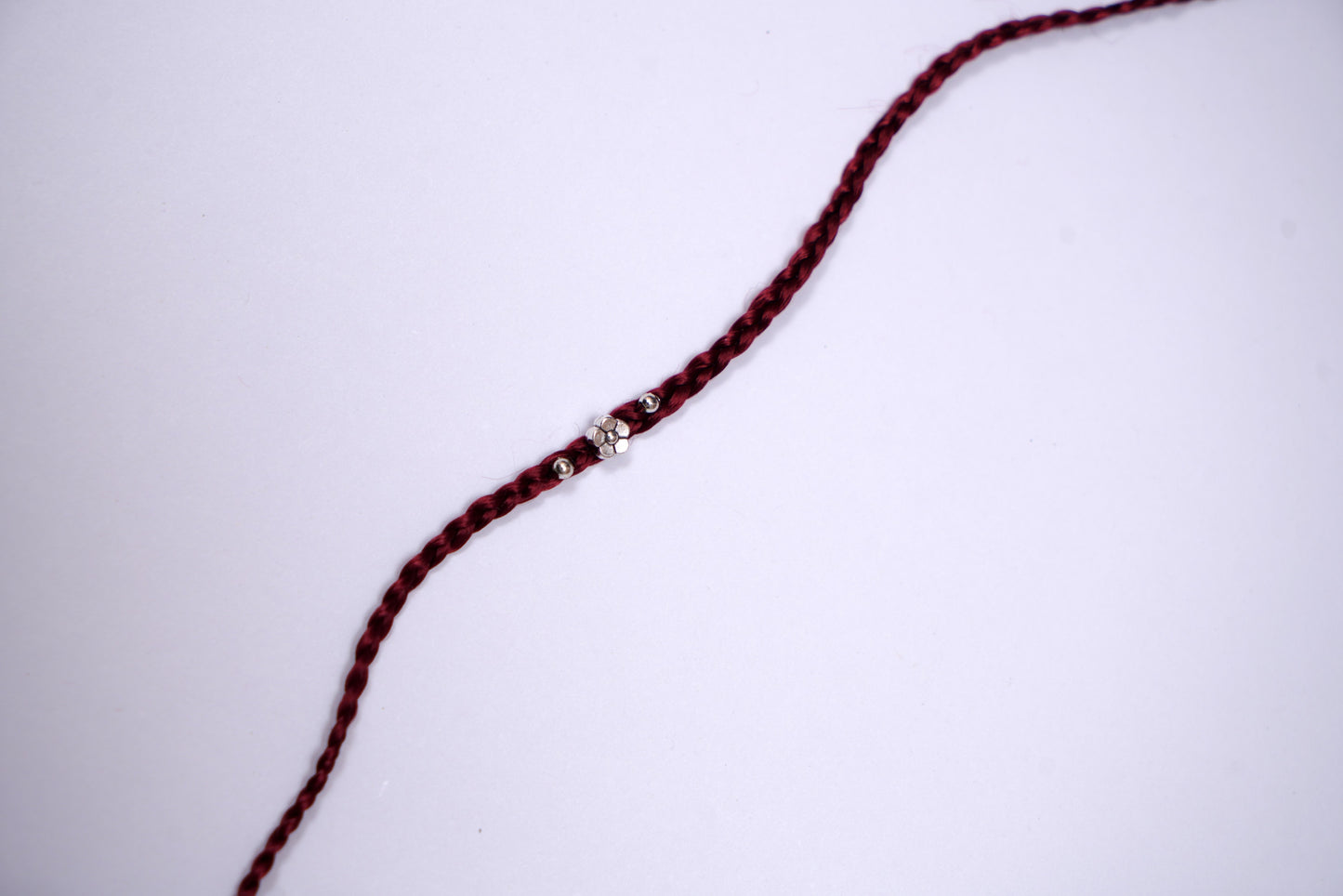 Maroon Braided Silk Thread Rakhi with Silver Floral Charm
