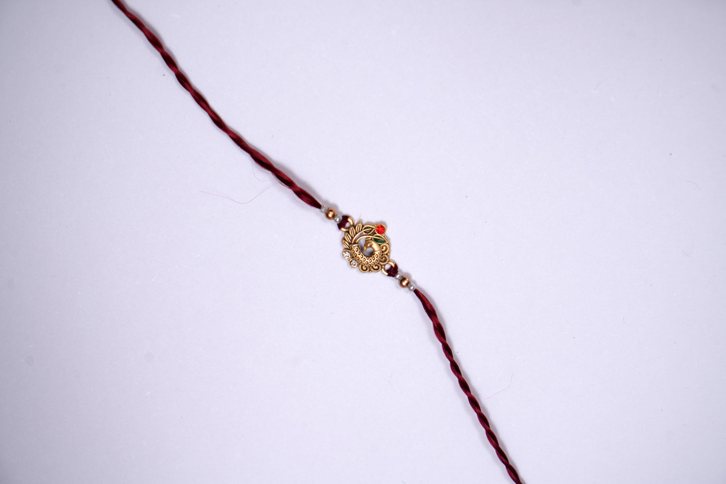 Maroon twisted Silk Thread Rakhi with Peacock Charm